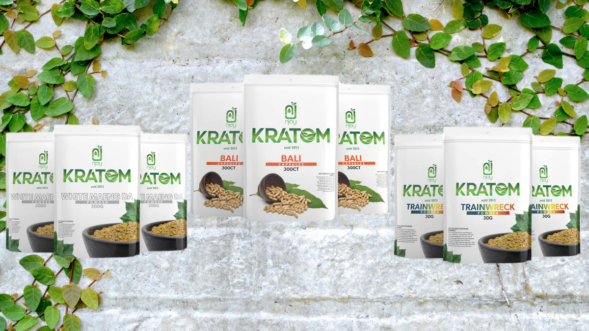 NJoy Kratom product lineup showing various powder bags and capsule bottles with different strains including Maeng Da Bali and Trainwreck